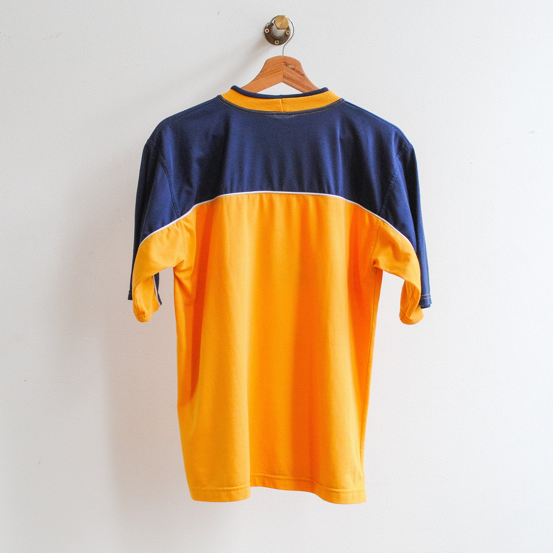 back of a vintage adidas thirt with top half in dark blue and bottom half in orange