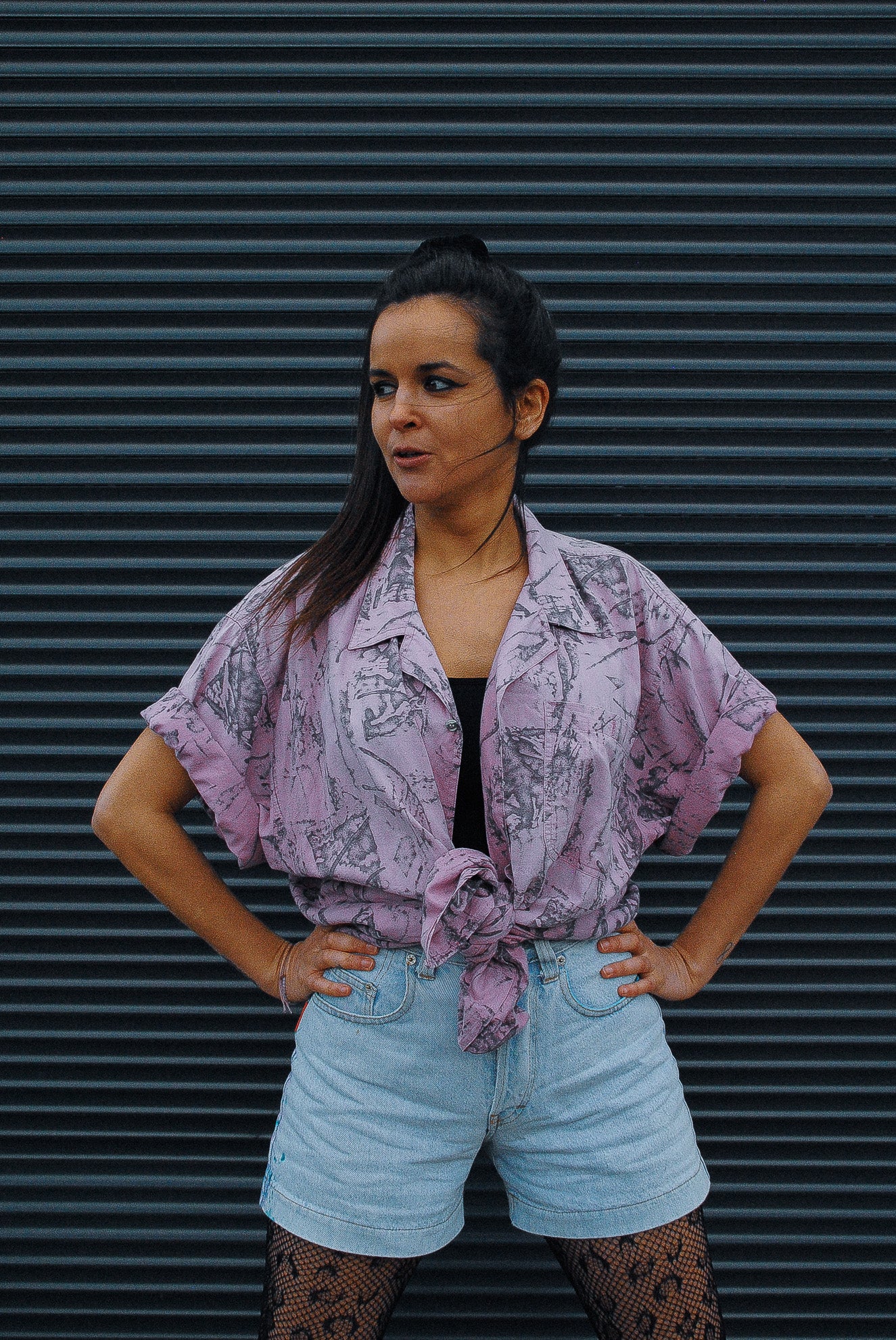 Model-in-front-of-garage-door-wearing-vintage-shirt-and-fresh-vintage-art-wear-jeans-short-in-light-jeans-color