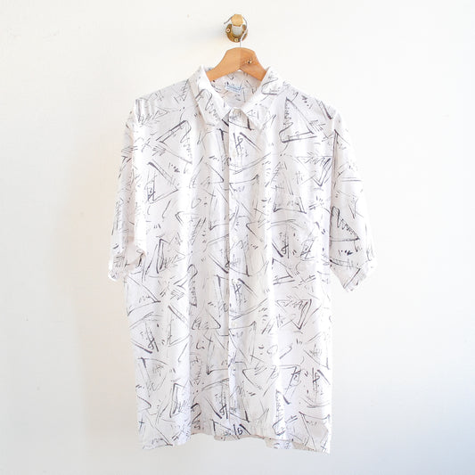 White vintage shirt with black abstract pattern in 80s 90s style on a hanger